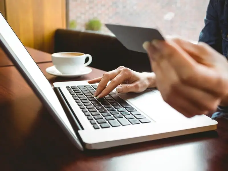 Person entering payment card details while typing on a laptop keyboard