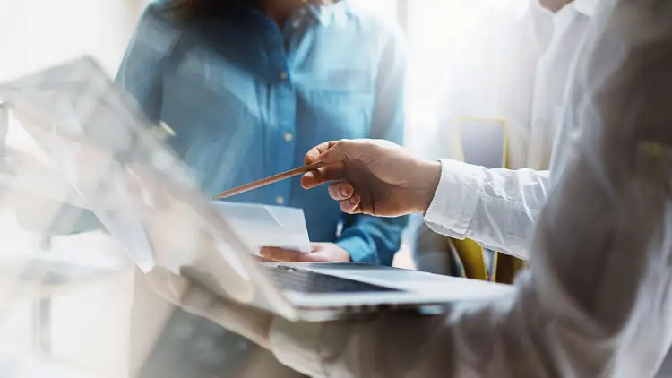 Procurement professionals reviewing a document and laptop during a sourcing discussion