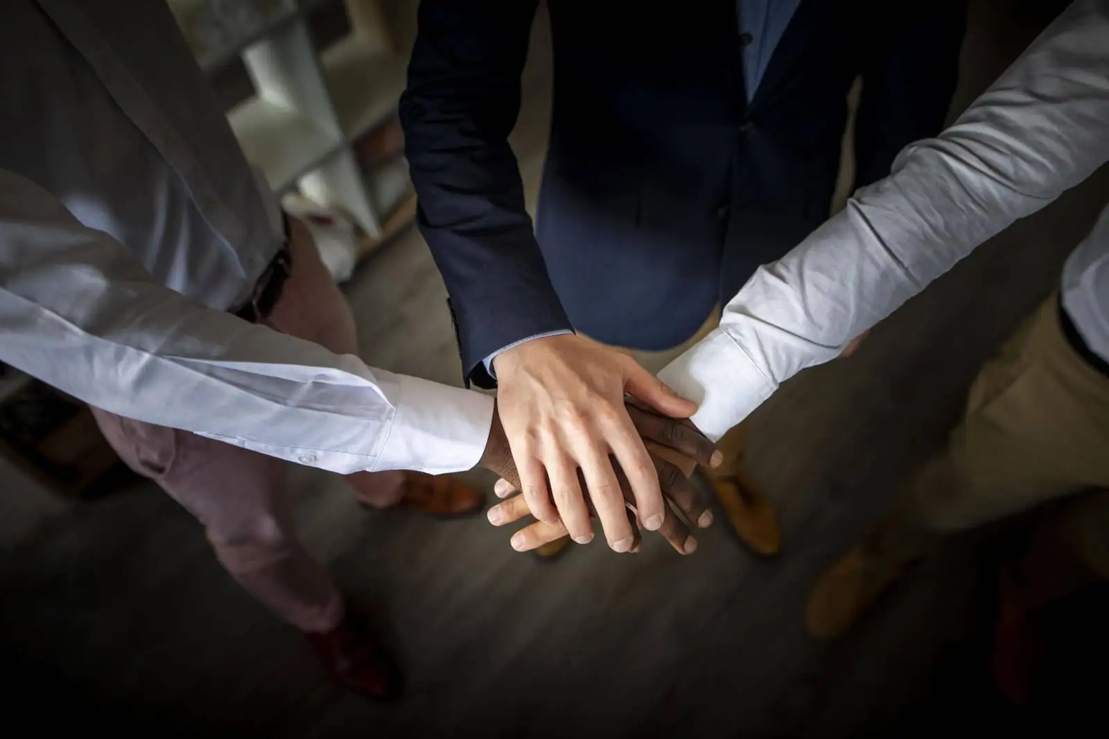 Three business colleagues stacking hands together in a team huddle