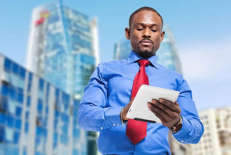 Business professional reviewing supplier spend data on a tablet in front of office towers