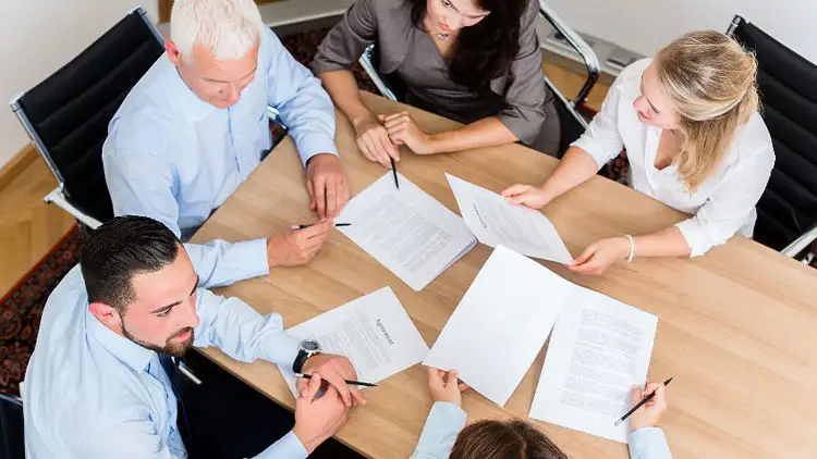 Overhead view of a legal team reviewing contract documents around a table