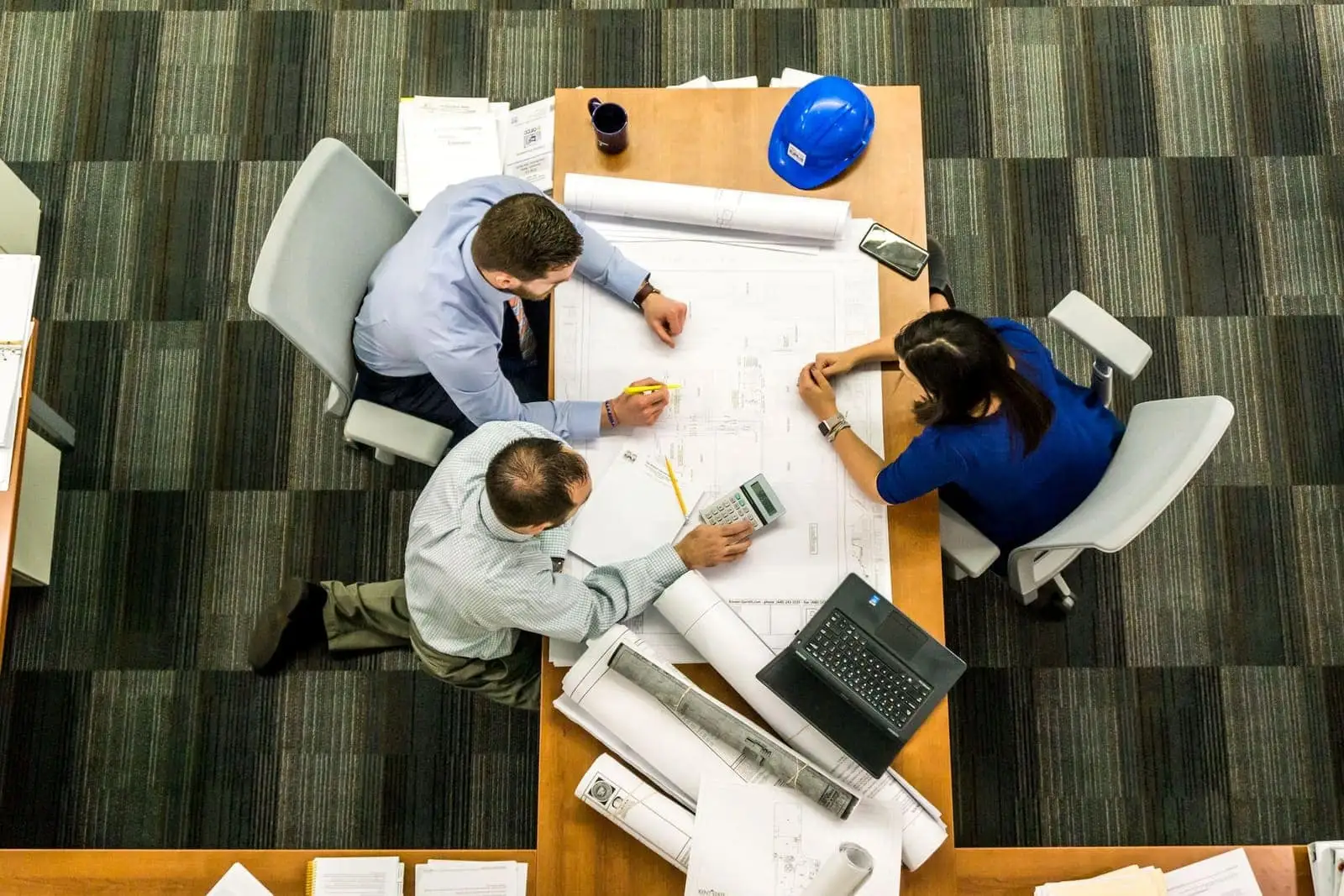 Overhead view of a team reviewing project blueprints and plans at a table
