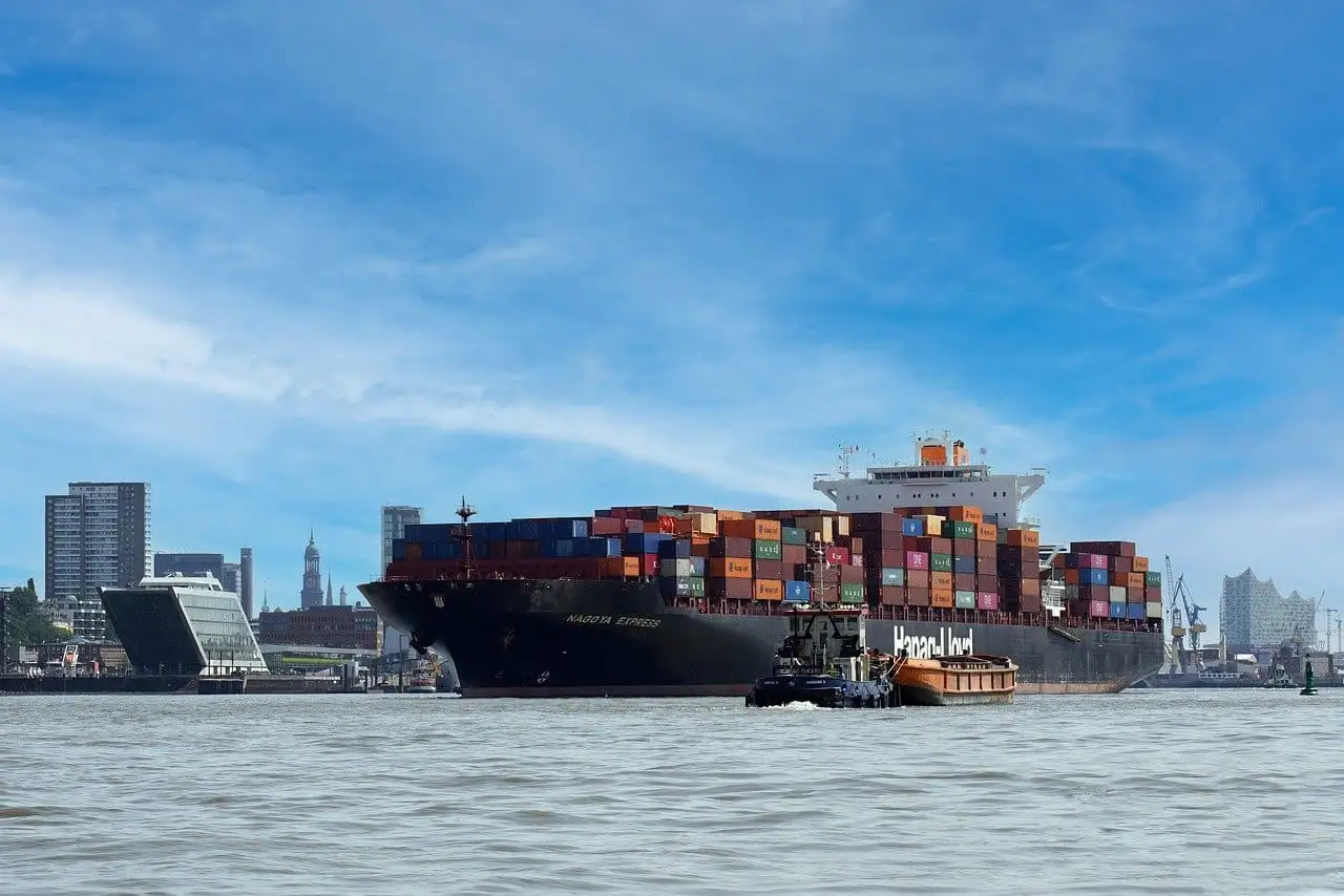A container ship loaded with cargo docked in a city harbor