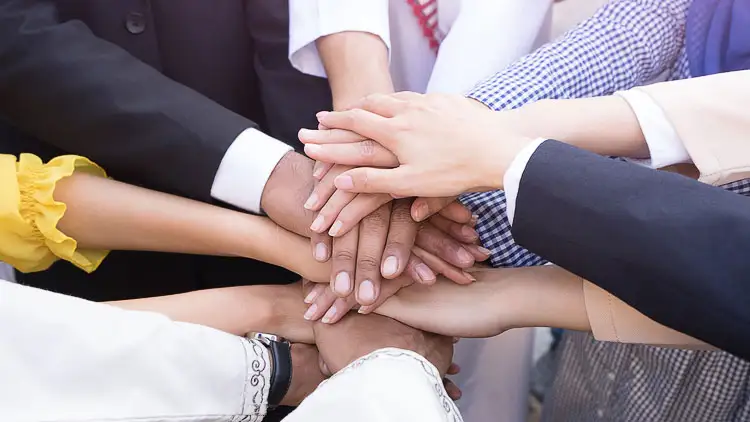 Diverse group of business professionals stacking hands in a team huddle
