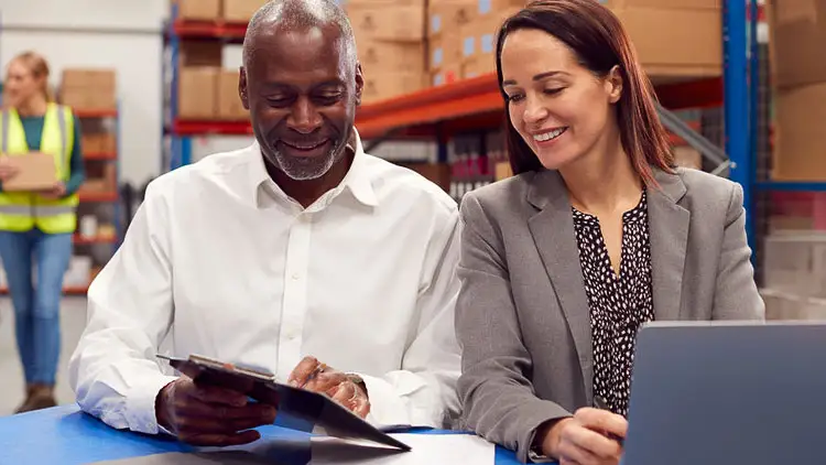 Two supplier partners review documents together on a warehouse floor