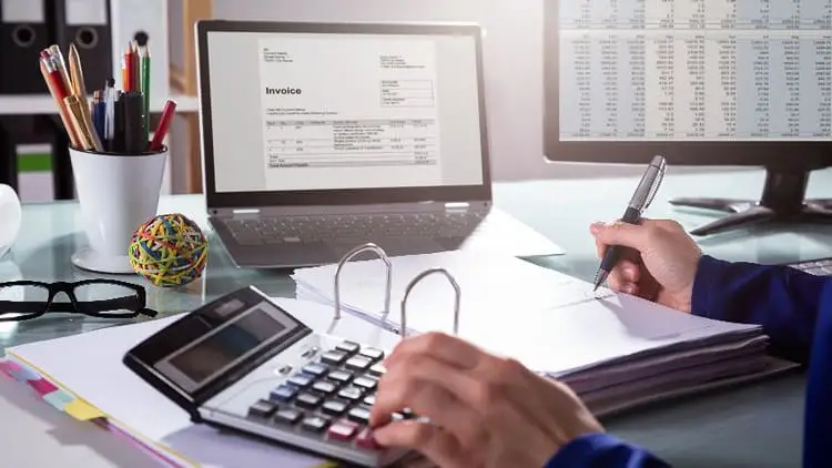Accounts payable clerk reviewing a digital invoice on a laptop screen